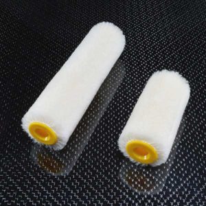 To Velourruller - 10 stk hvide malerruller med gul inderside fra boatkitshop.com er placeret diagonalt på en mørk, struktureret og let reflekterende overflade.